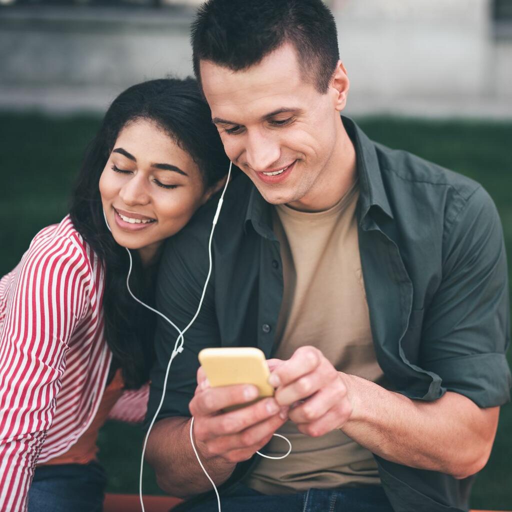Young man and woman listening to music on headphones